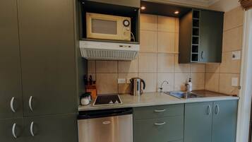 A kitchen with green cabinets, a microwave, a dishwasher, and a sink.