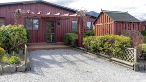 Un bâtiment en bois rouge, doté d’un porche couvert et d’une allée gravillonnée.