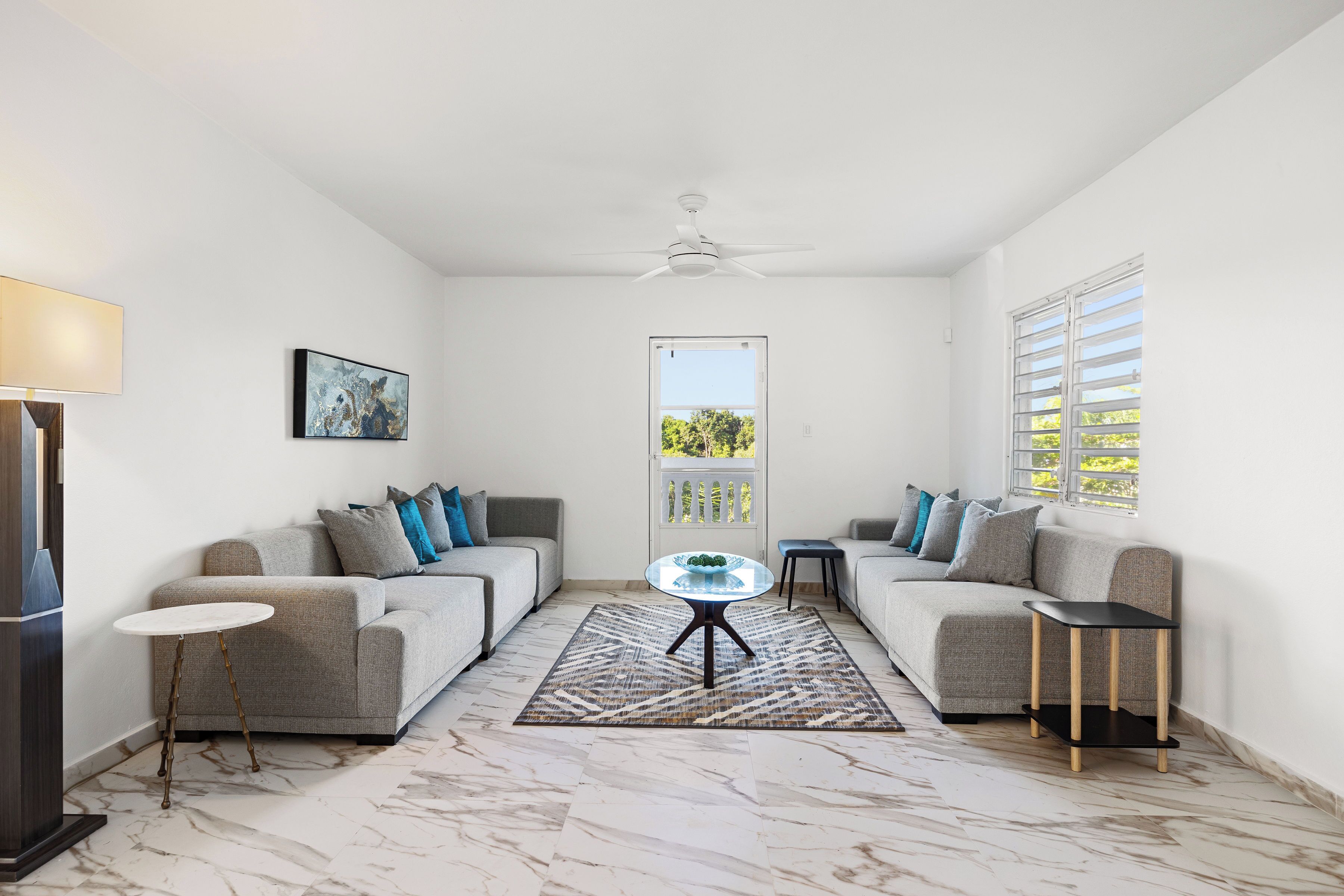 A living room with two sofas, a coffee table, a side table, and a ceiling fan.