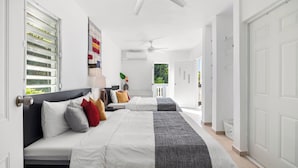 Un dormitorio con dos camas, ventilador de techo y vista al exterior.