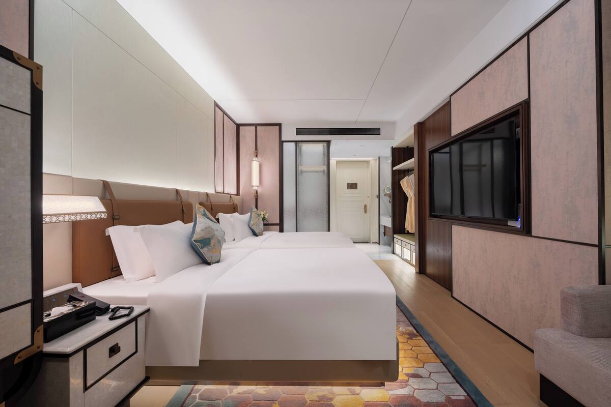 Una habitación de hotel con una cama grande, mesitas de noche, un televisor y un armario.