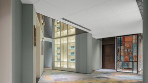 A hallway with a patterned floor, a glass door with a decorative design, and a wall with a colorful poster. - Shantou DIOTEL Queen Hotel (Shantou)