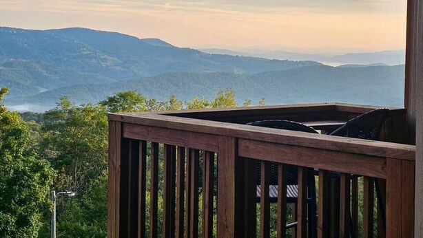 A wooden deck with a view of distant mountains and a cloudy sky.