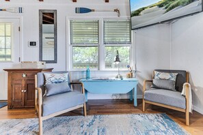 A room with a wooden desk, two chairs, a small table, and a window with blinds. - Oak Island Escape-2nd Row, Pet-Friendly w/ Ocean Views & Boat Ramp Nearby (Oak Island)
