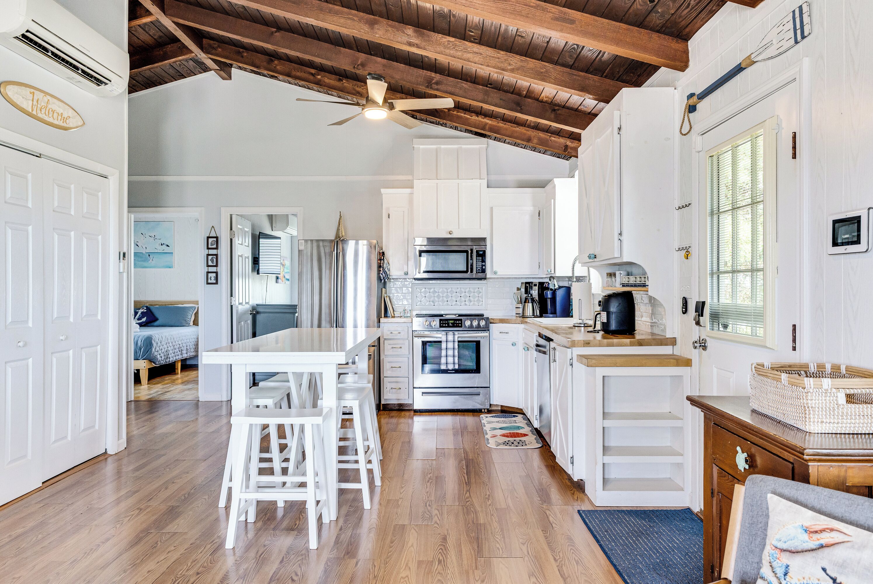 A modern kitchen with white cabinetry, stainless steel appliances, and a wooden ceiling.