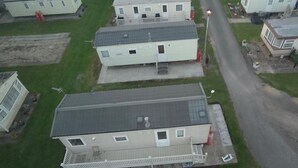 Una fila de casas móviles con porches adosados, un camino pavimentado y una calle visible al fondo.