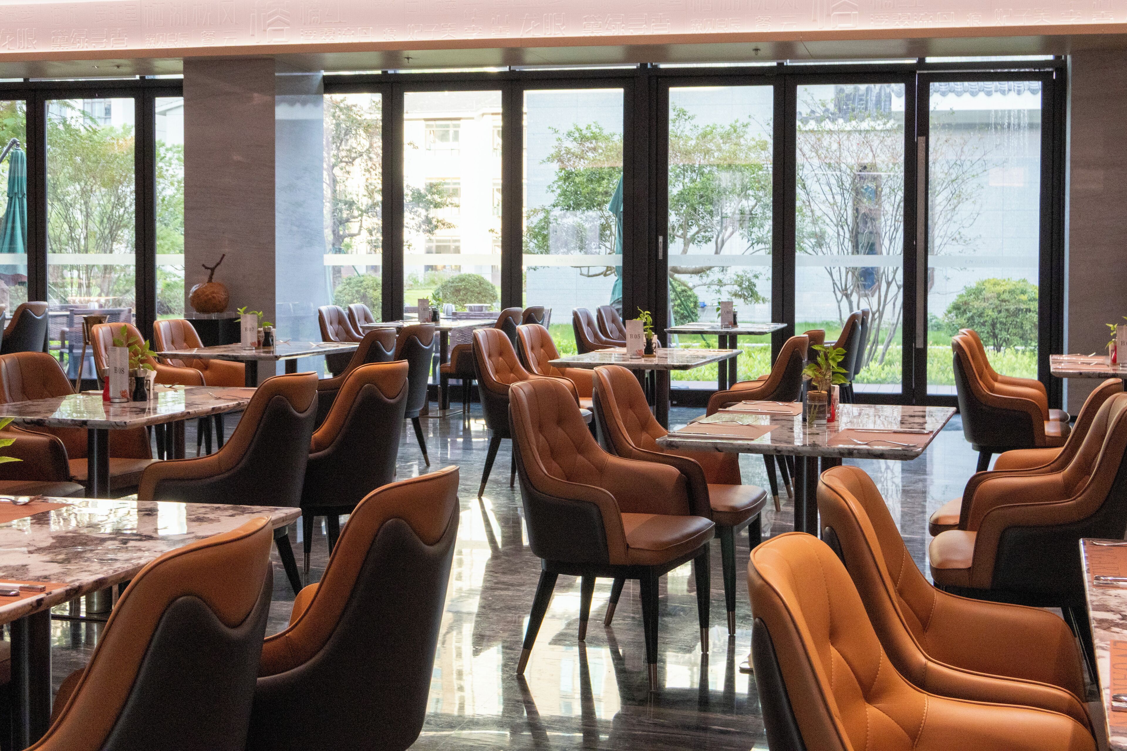 Un ristorante spazioso con numerosi tavoli e sedie, ampie finestre che offrono vista sull'esterno.