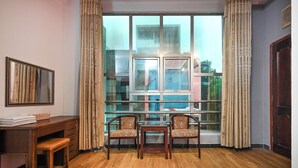 A hotel room with a wooden desk, two chairs, a bed, and a large window with curtains. - Hoang Phung Hotel - Tan Son Nhat Airport (Ho Chi Minh City)