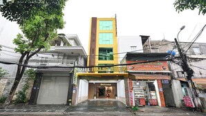 A hotel with a yellow facade, a closed shutter on the left, and a signboard with the hotel's name. - Hoang Phung Hotel - Tan Son Nhat Airport (Ho Chi Minh City)
