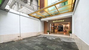 A hotel entrance with a 'Welcome' sign, a reception desk, and potted plants. - Hoang Phung Hotel - Tan Son Nhat Airport (Ho Chi Minh City)