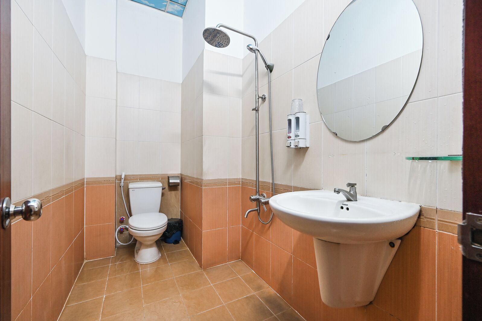 A bathroom with a toilet, a sink, a shower, and a mirror.