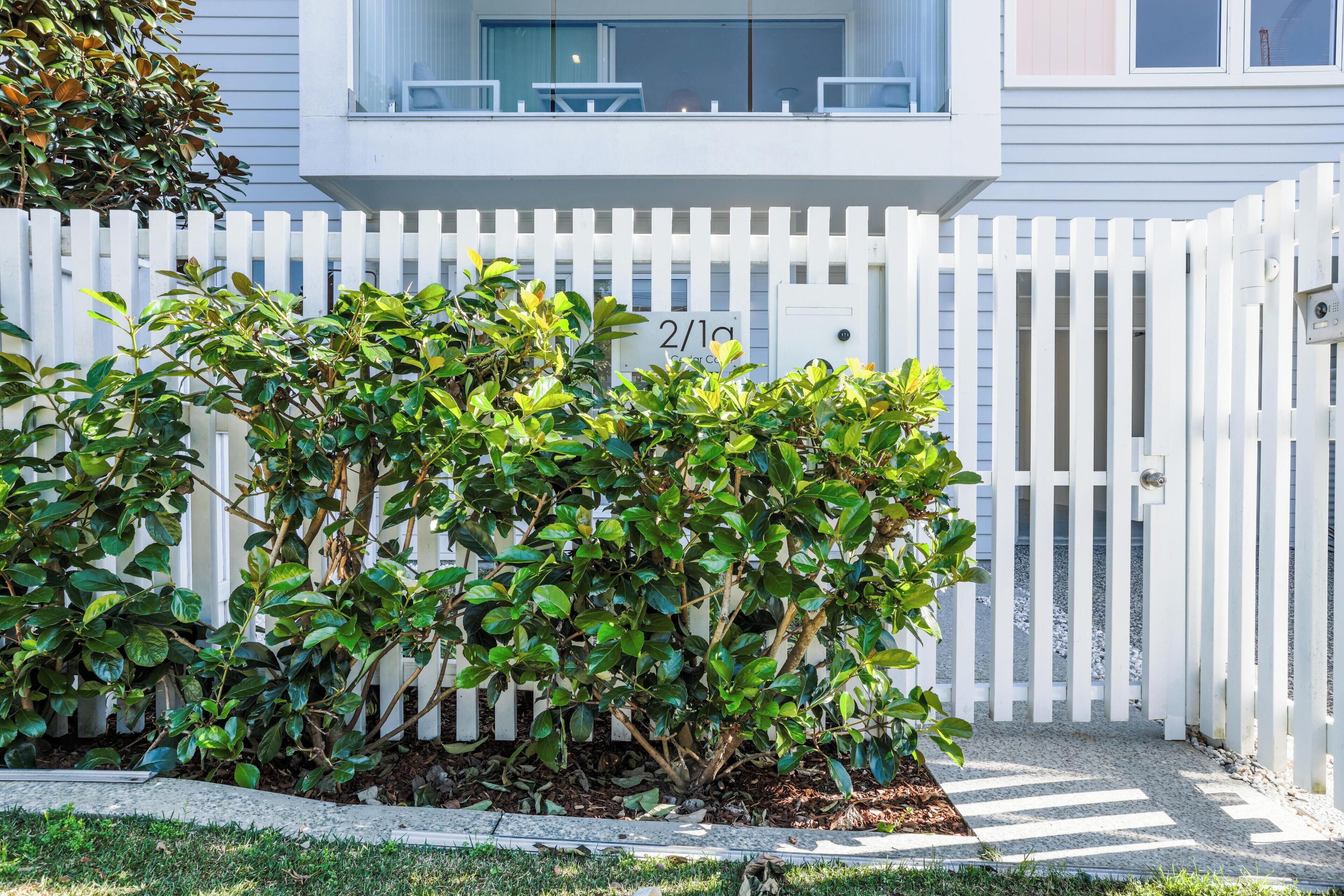 A white picket fence with a mailbox labeled "2/19" in front of a house.