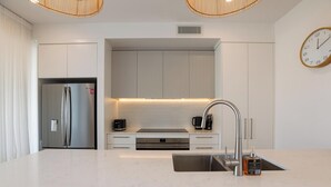 Een moderne keuken met een roestvrijstalen koelkast, een inbouwoven, een spoelbak en een klok aan de muur.