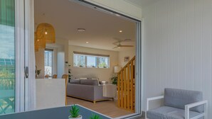 Een moderne woonkamer met een bank, een eettafel met potplanten, een trap en uitzicht op buiten.