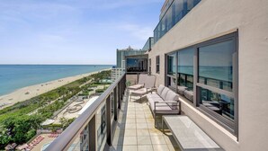 A balcony with a view of the beach and ocean, outdoor seating, and a pool area. - Stylish Oceanfront 2 BR 1.5 BA Condo with Resort Amenities, Pools, Gym, Sauna 1402 (Miami Beach)