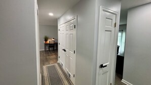 A hallway with two white doors, a desk with a lamp, and a plant.