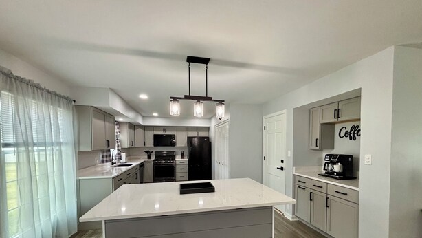 A modern kitchen with a central island, stainless steel appliances, and a coffee station.