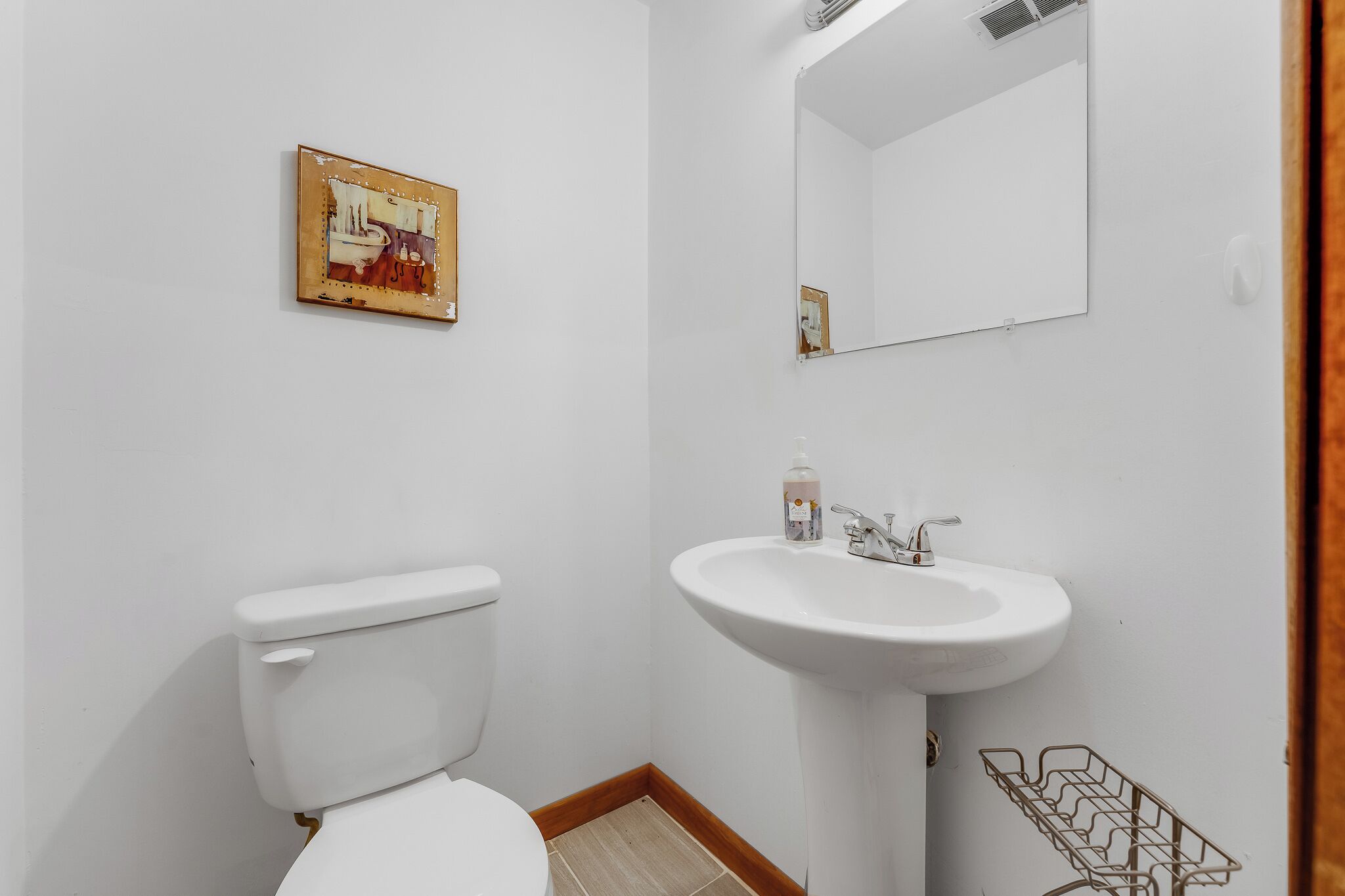 Un bagno piccolo e pulito, con il water, il lavandino e uno specchio.