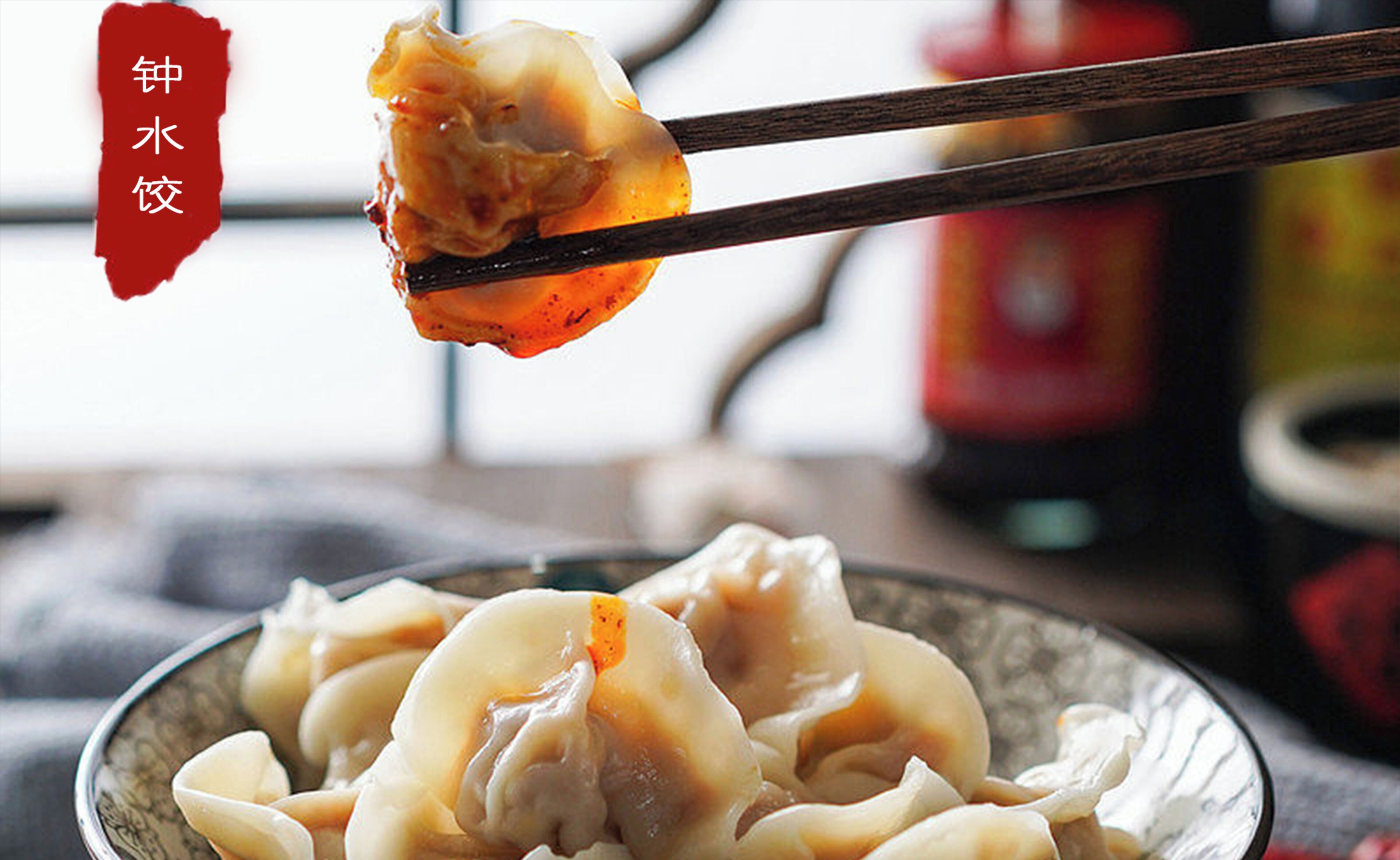 A bowl of dumplings with chopsticks lifting one.