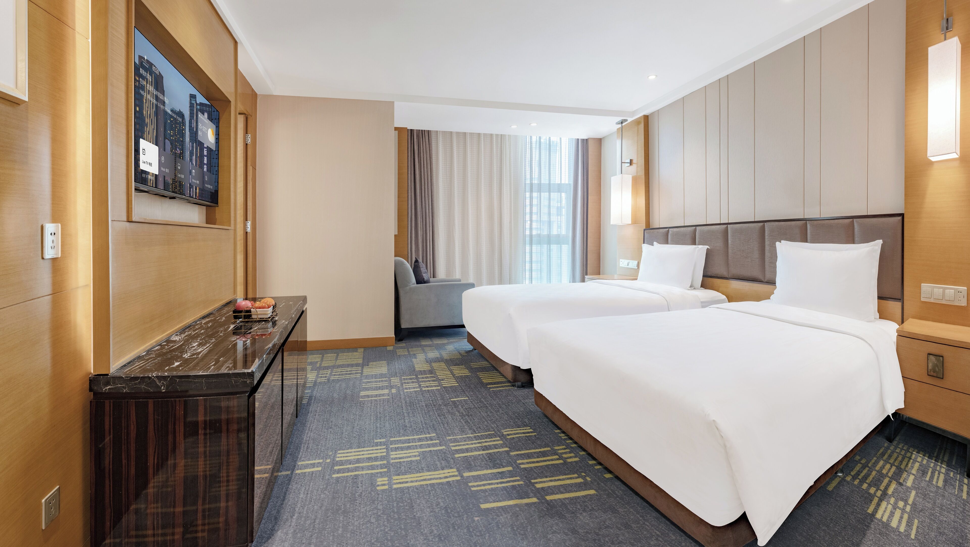 Une chambre d’hôtel avec deux lits, un bureau avec un ordinateur, une chaise et une grande fenêtre avec des rideaux.