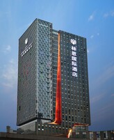A tall hotel building with a distinctive facade featuring a geometric pattern and a prominent vertical red structure.
