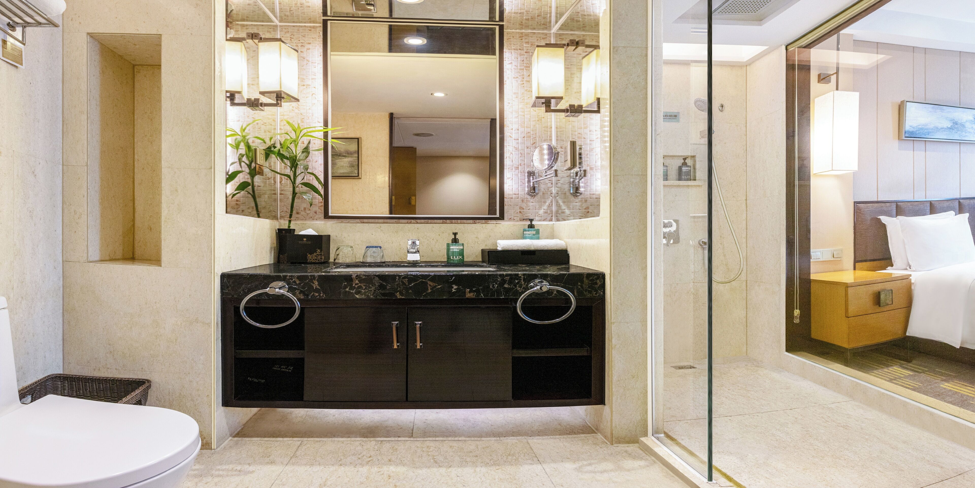 Un baño moderno con tocador de mármol, un espejo grande y cabina de ducha con mampara de vidrio.