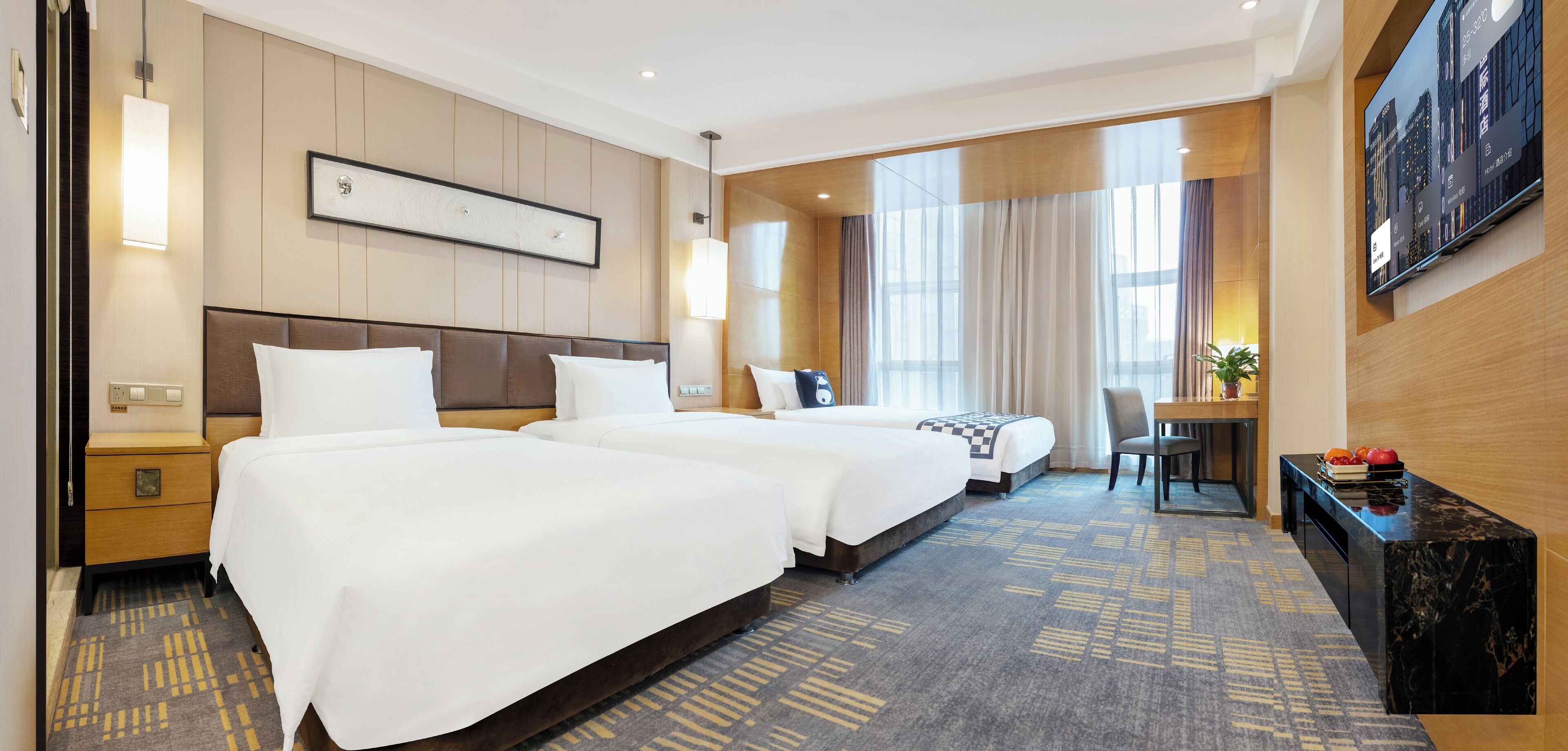 Ein Hotelzimmer mit zwei Betten, einem Schreibtisch, einem Stuhl, einem Fernseher und einem großen Fenster mit Vorhängen.