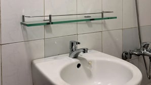 A bathroom with a white sink, a round mirror, and a glass shelf. - Moc Truly Hue Homestay (Hue)