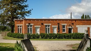 A brick building with multiple windows, a door, and a chimney. - Historic Castle Coach House – Trail & Wineries (Earnscleugh)