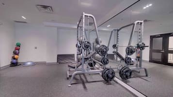 Ein Fitnessstudio mit Krafttrainingsgeräten, Übungsbällen und einem Spiegel.