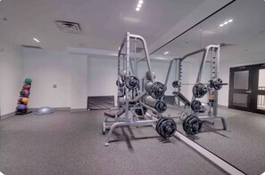 Un gimnasio con equipamiento para levantamiento de pesas, pelotas de ejercicio y un espejo.