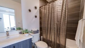 Ein modernes Badezimmer mit Duschvorhang, Toilette und einem Waschtisch mit Pflanzen.