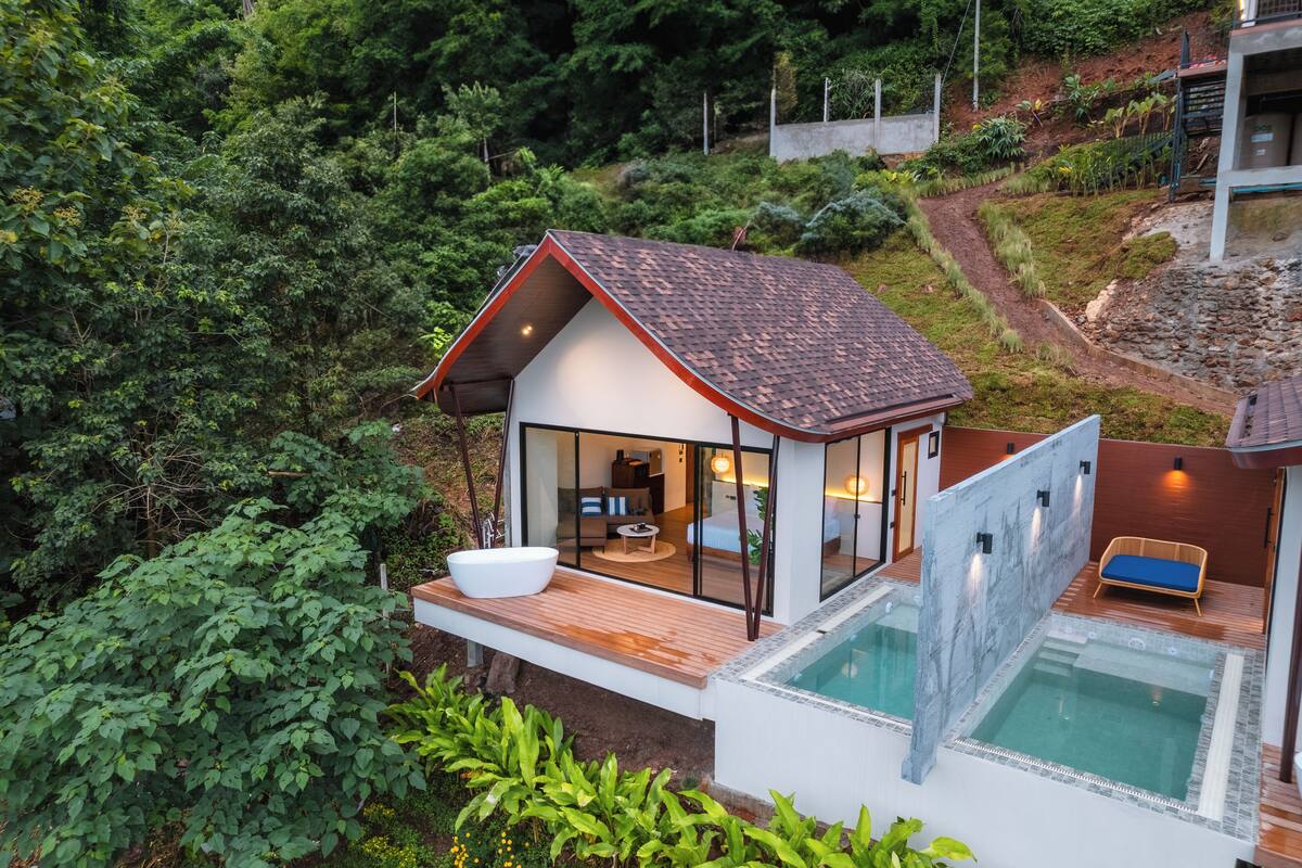 A modern house with a pool, a dining area, and a bedroom with a large window.