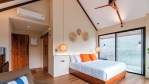 Un dormitorio moderno con una cama de madera, un sofá, una mesa de centro redonda y un ventanal grande.