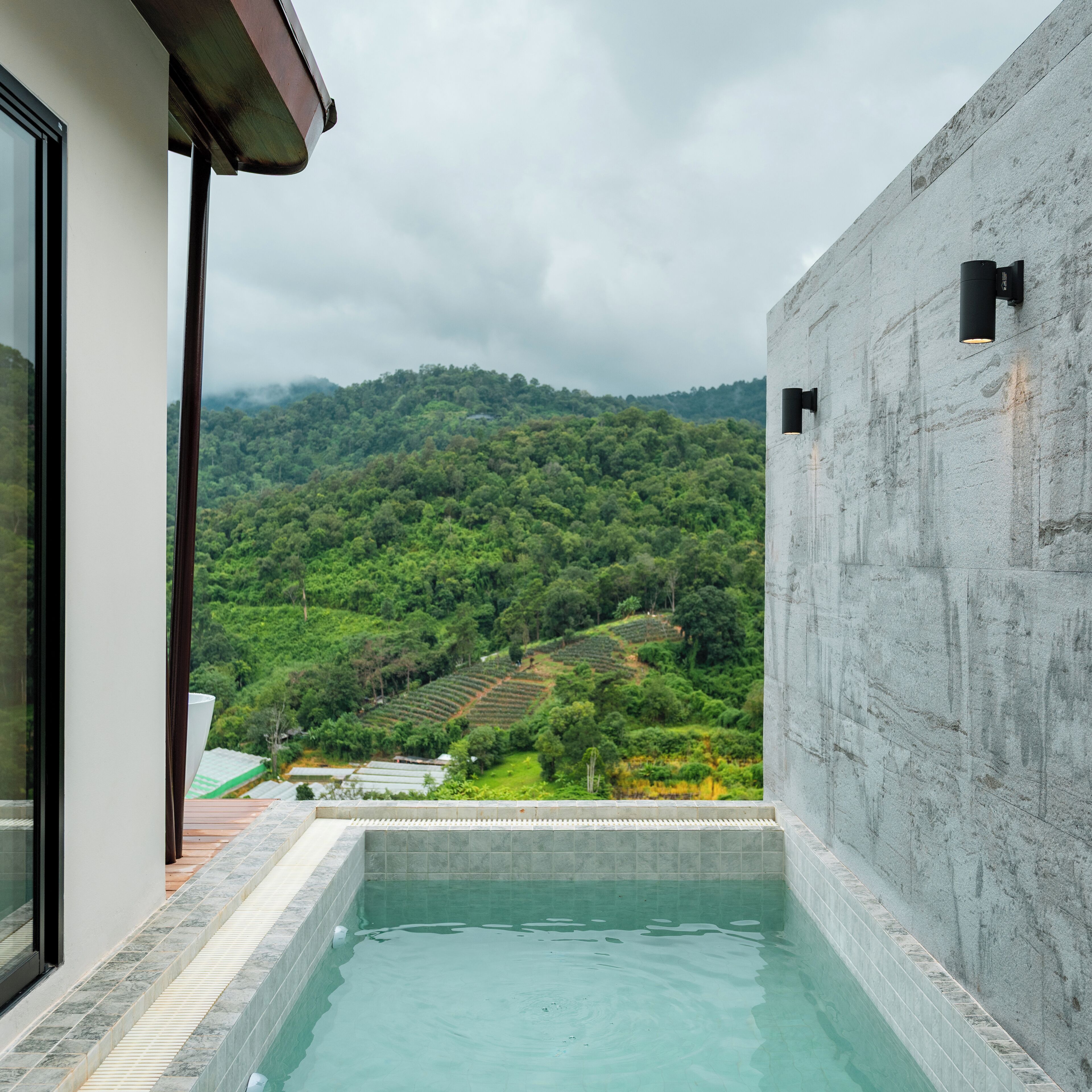 A modern outdoor pool with a view of a lush green hillside.