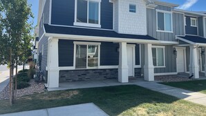 A modern two-story residential building with a stone foundation, large windows, and a well-maintained lawn.