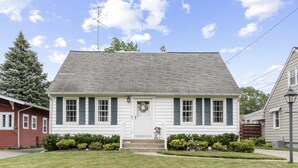Ein zweistöckiges Haus mit Veranda, kleinem Garten und blauem Himmel.