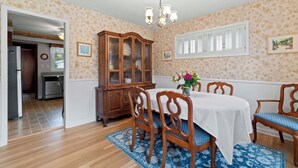 Ein Esszimmer mit einem Holzkabinett, einer Kristallleuchtre und einem Esstisch mit Stühlen.