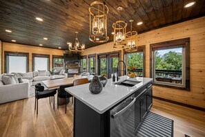 Una cucina moderna con isola centrale, soffitto in legno e ampie finestre che si affacciano sul verde.