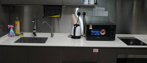 A kitchen with a microwave, toaster, sink, and stainless steel cabinets.