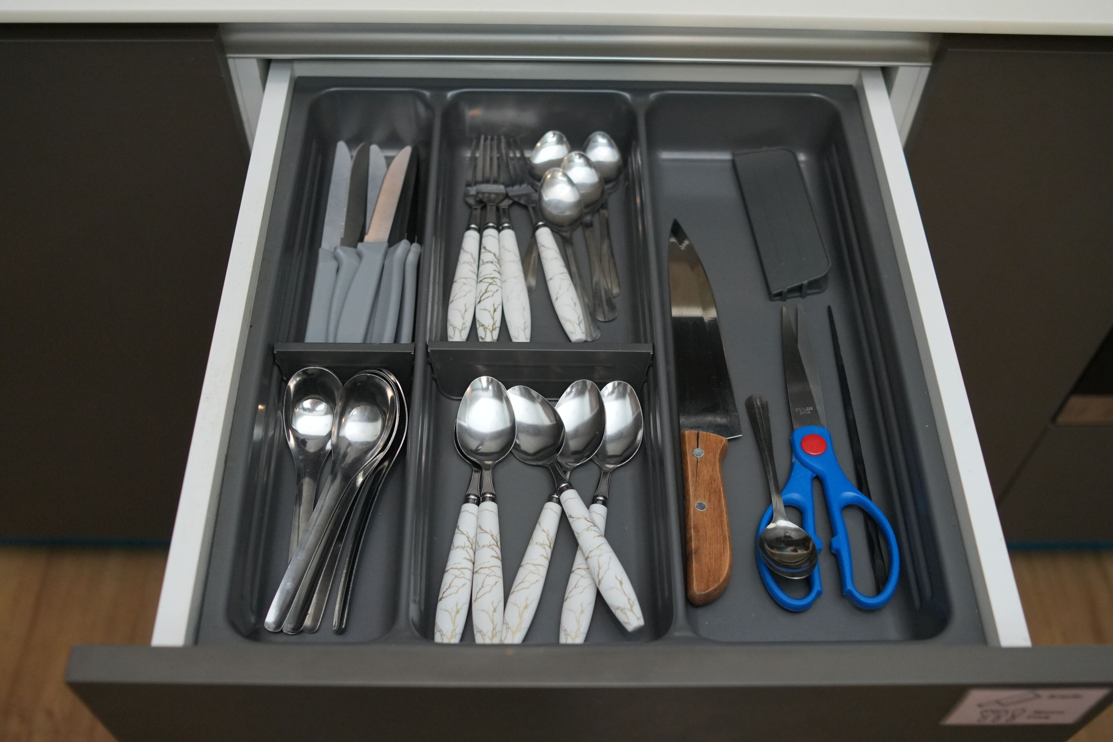 A drawer with utensils and a knife.