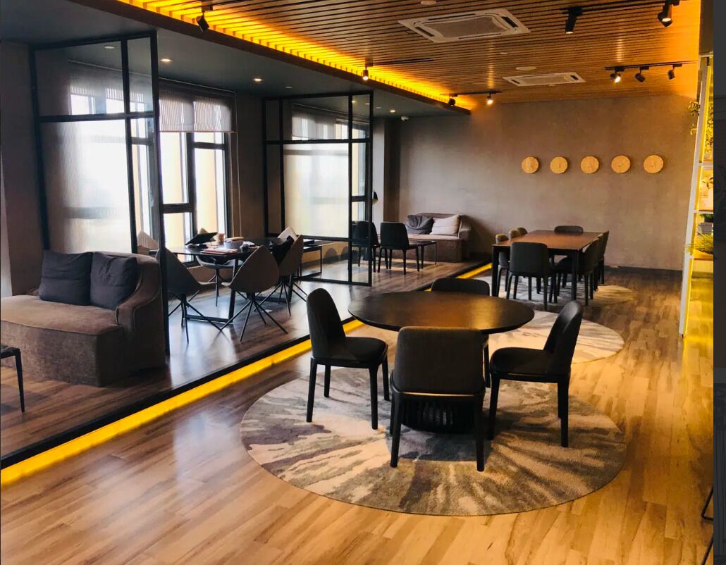 Une salle de réunion moderne avec une table ronde, des chaises noires, un canapé et un tapis à motifs.
