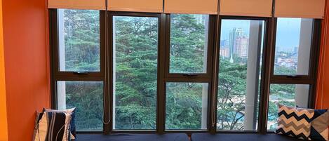 A room with a large window, two black cushioned seating areas, and orange walls.