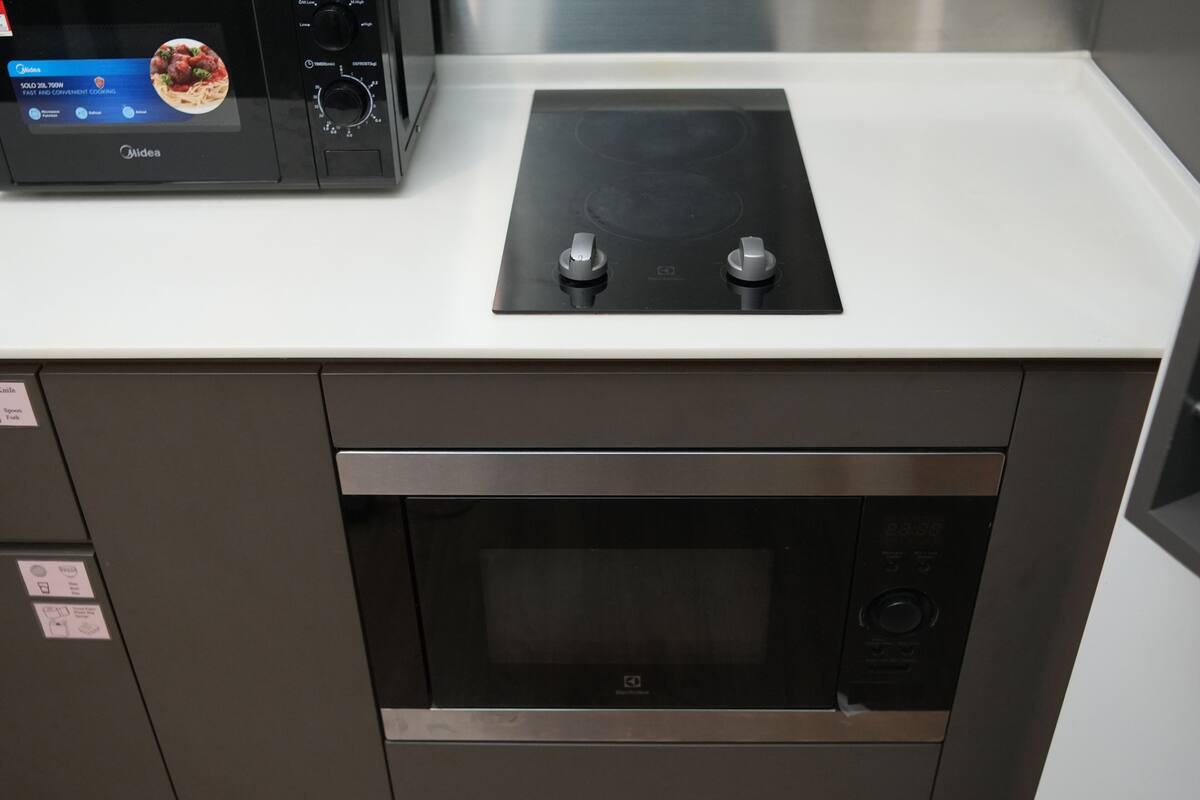Een keuken met een ingebouwde magnetron, een inductiekookplaat en een roestvrijstalen oven.