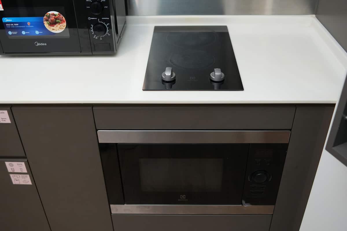 A kitchen with a built-in microwave, an induction cooktop, and a stainless steel oven.