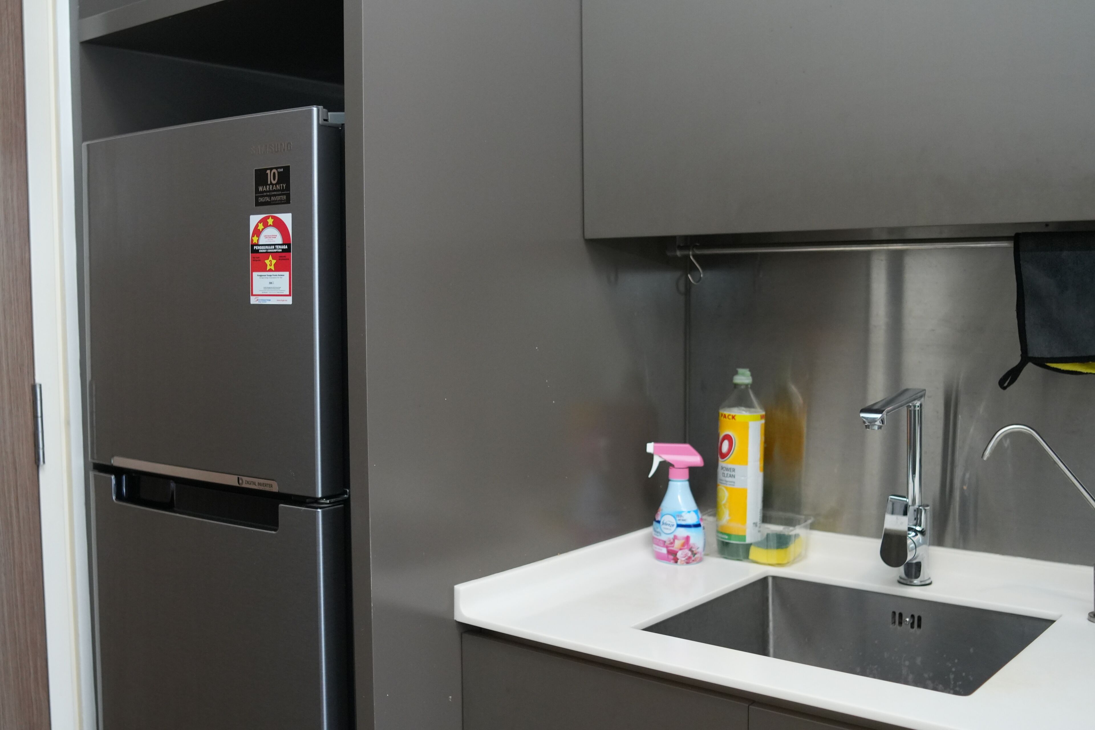 Ein Edelstahl-Kühlschrank, ein weißes Spülbecken und Reinigungsmittel.