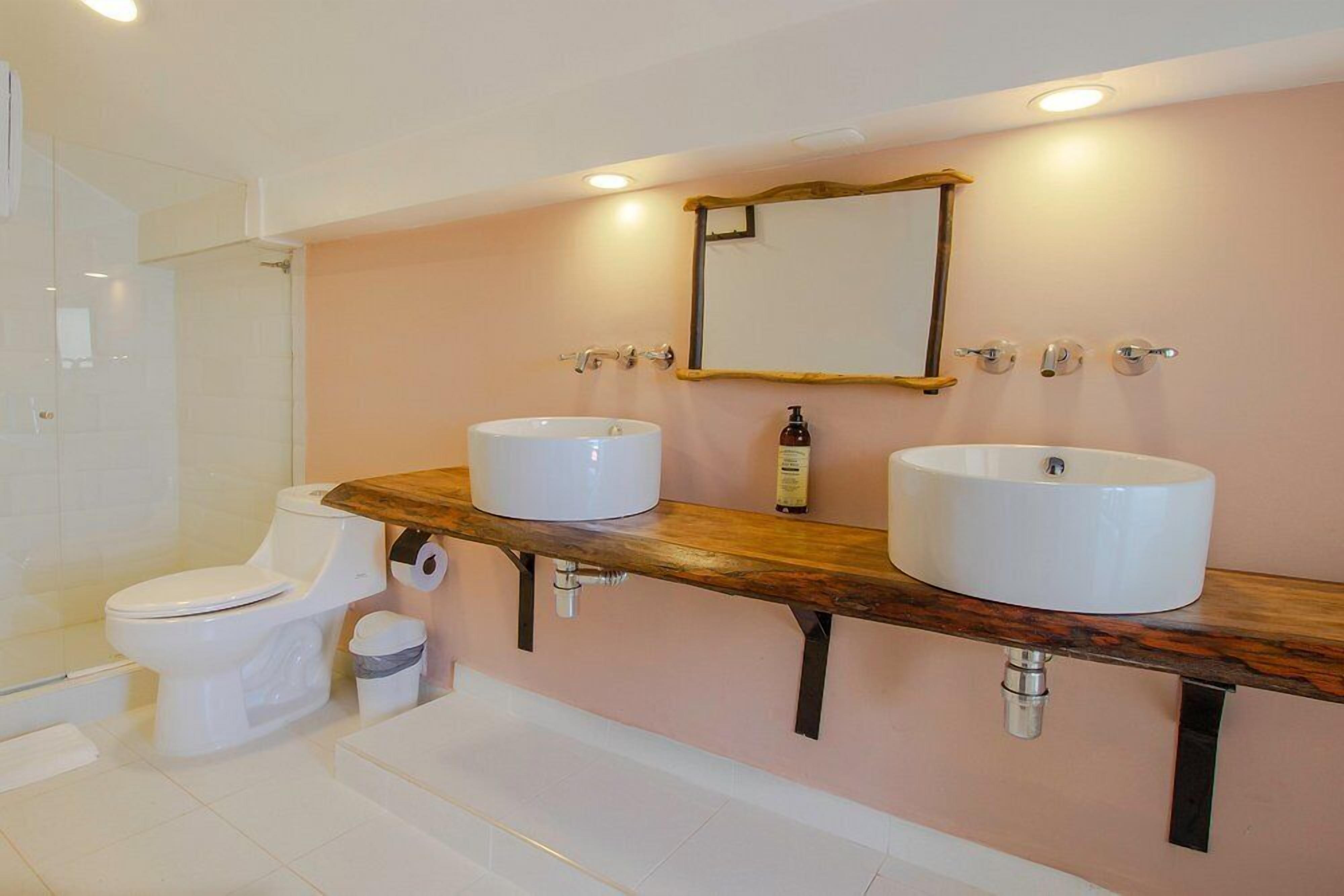Une salle de bain avec deux lavabos, des toilettes et une douche.