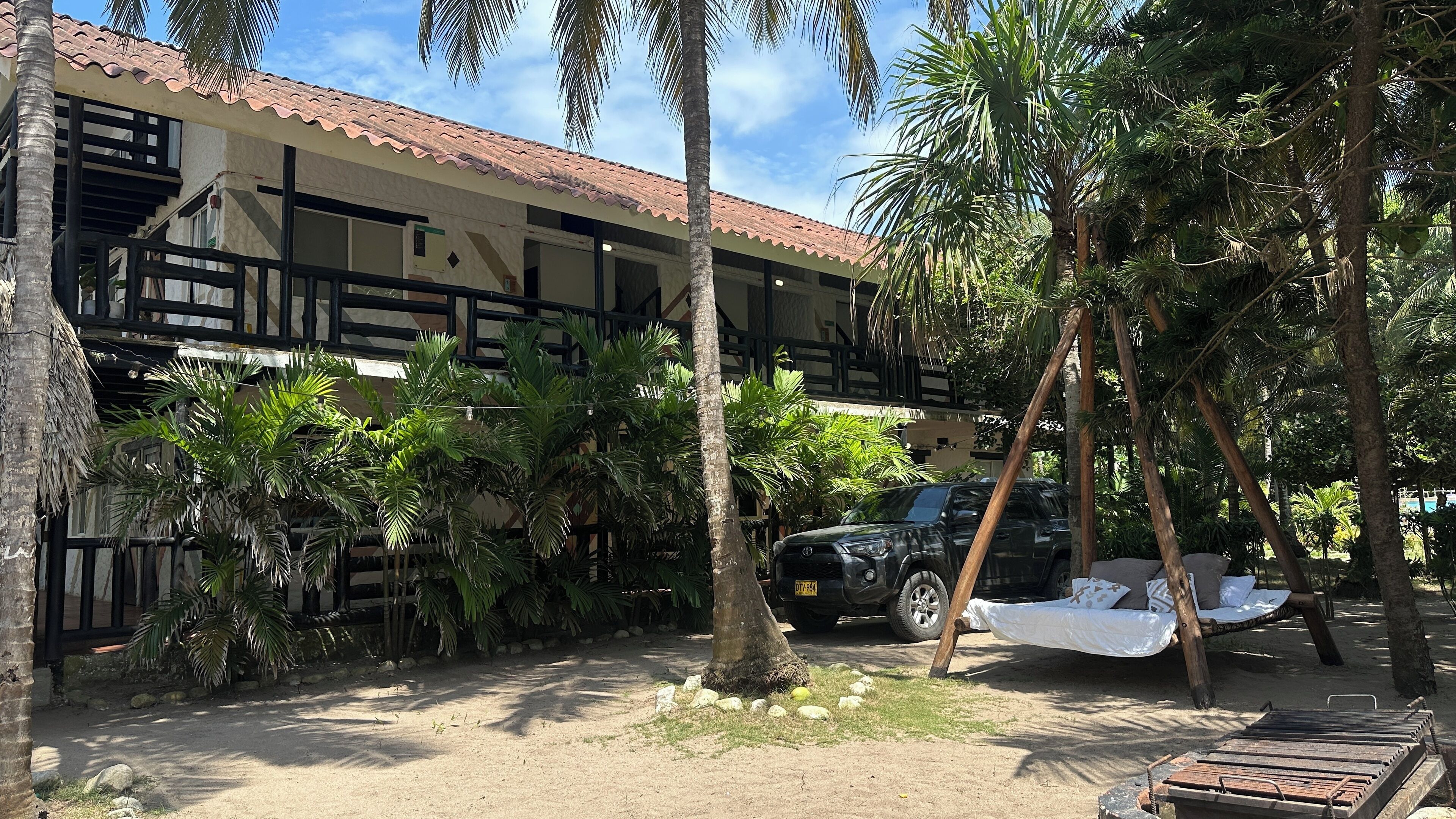 A hotel with a tiled roof, multiple balconies, and lush tropical vegetation.