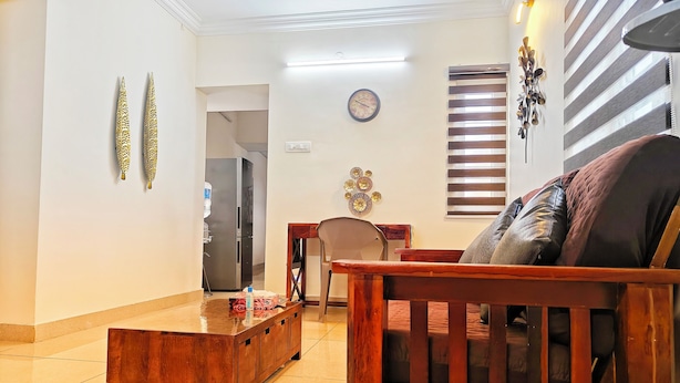 Una sala de estar con un sofá de madera, una mesa de centro, una mesa de comedor con sillas, un refrigerador y decoración en las paredes.