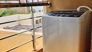 Una habitación con ventana, lavadora y vistas a edificios.